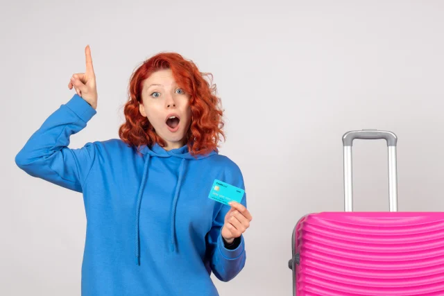 Mulher ao lado de mala de viagem segurando cartão com o Programa de Milhas Livelo