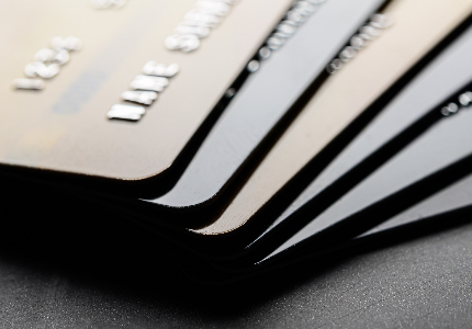 Cartões de crédito premium empilhados sobre mesa escura, representando cartão Black, benefícios exclusivos e alto limite para clientes de alta renda.