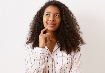 Mulher jovem pensativa olhando para cima, representando dúvida sobre qual cartão de crédito escolher e decisão financeira estratégica.