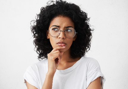 Mulher pensativa com expressão de dúvida segurando o queixo, representando questionamento sobre qual é o melhor dia para usar o cartão depois do fechamento da fatura.