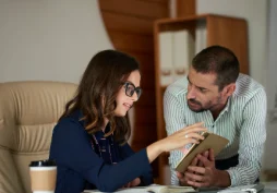 Casal analisando informações financeiras com consultor em tablet, representando avaliação de perfil bancário e análise de comportamento pelo banco.